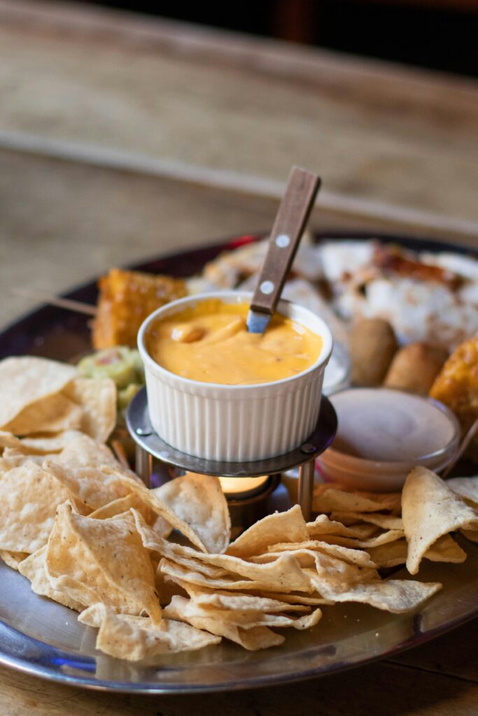 Close-up of tasty Mexican nachos served with a warm cheese dip on a wooden table.