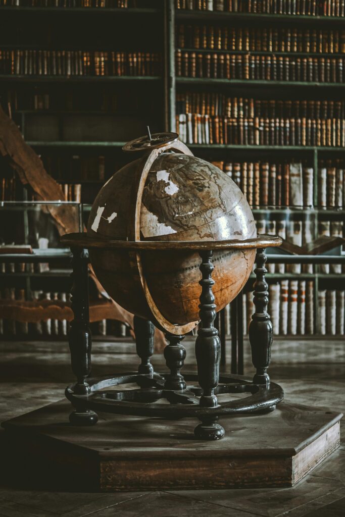 A vintage globe displayed in a historic library filled with old books.
