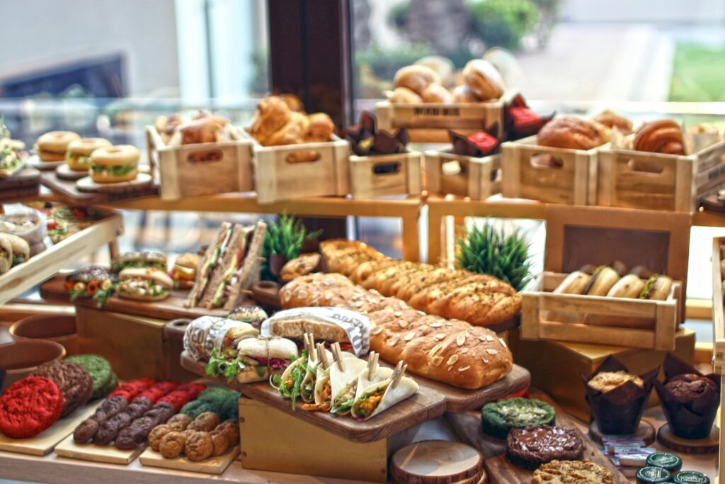 A vibrant display of assorted gourmet breads, sandwiches, and baked goods on wooden trays.