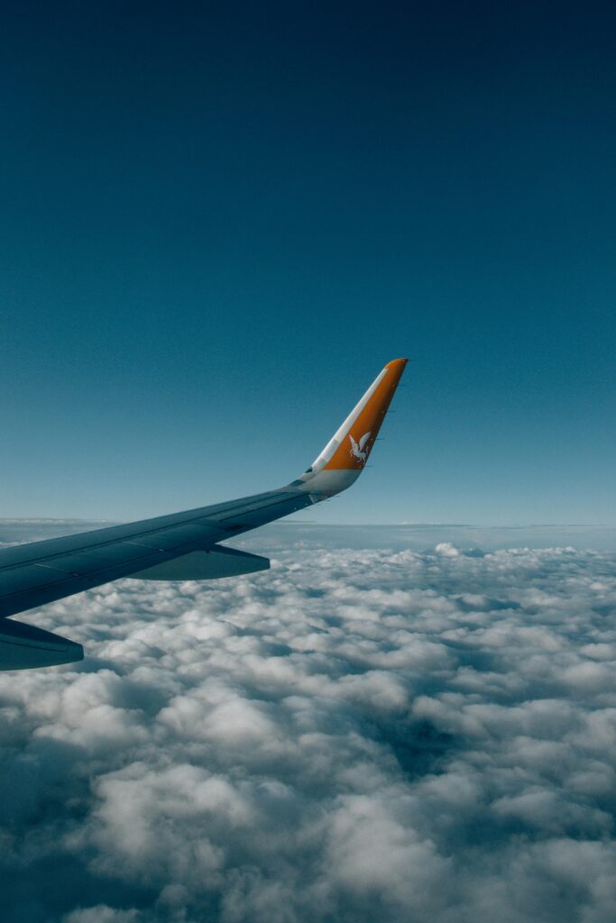 A tranquil aerial view of an airplane wing soaring above a sea of fluffy clouds.
