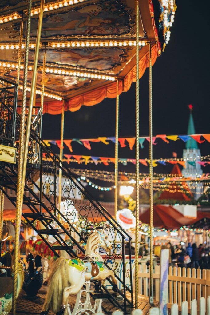 Enchanting carousel at night with colorful lights and decorations at a lively festival.