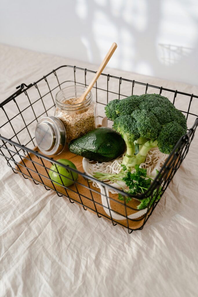Fresh broccoli, avocado, and oats ready for healthy meal preparations in a wire basket.