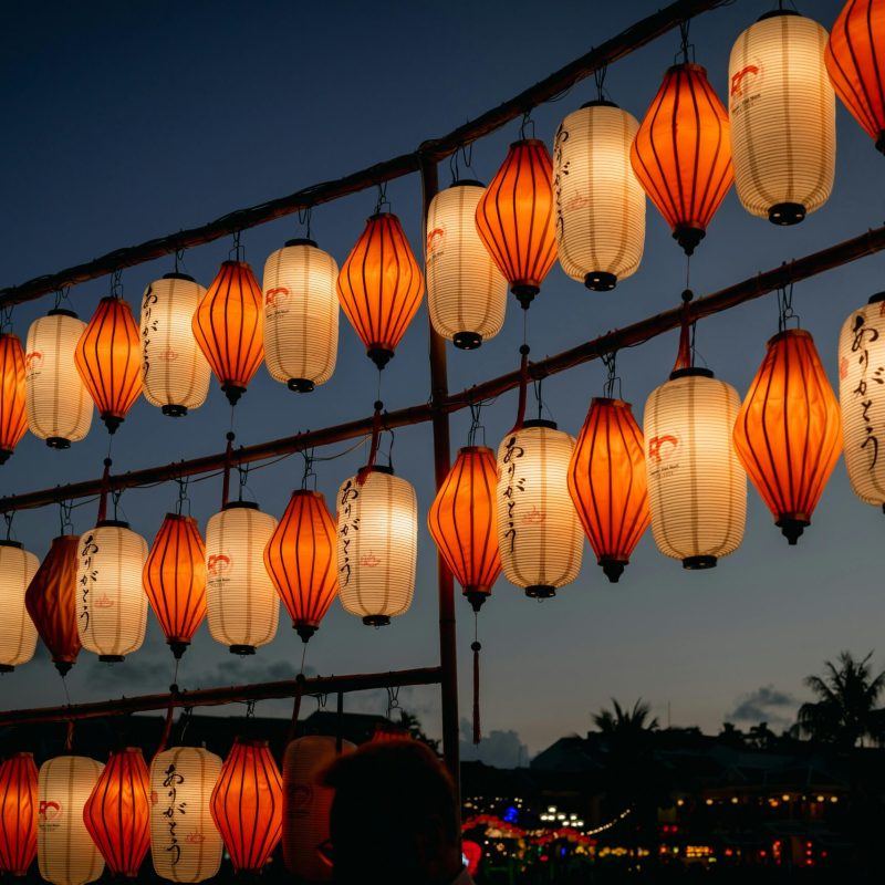 Beautiful display of orange and white lanterns hanging outdoors during a twilight festival.