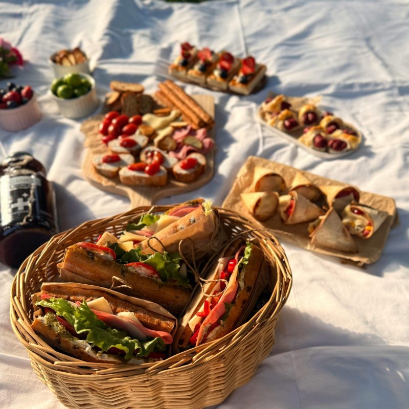 Delicious picnic spread with sandwiches and snacks on a blanket outdoors.