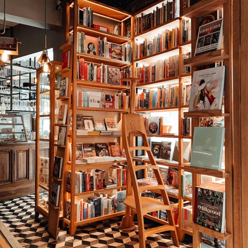 Wooden ladder placed near opened shelves with collection of various literature in traditional bookshop