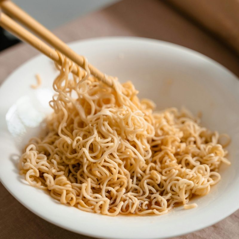 Close-up of savory noodles in a ceramic bowl with chopsticks, highlighting Asian cuisine.